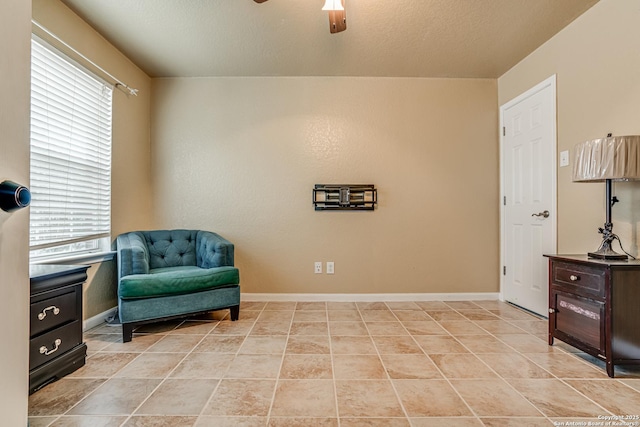 living area featuring light tile patterned floors, a textured ceiling, and ceiling fan