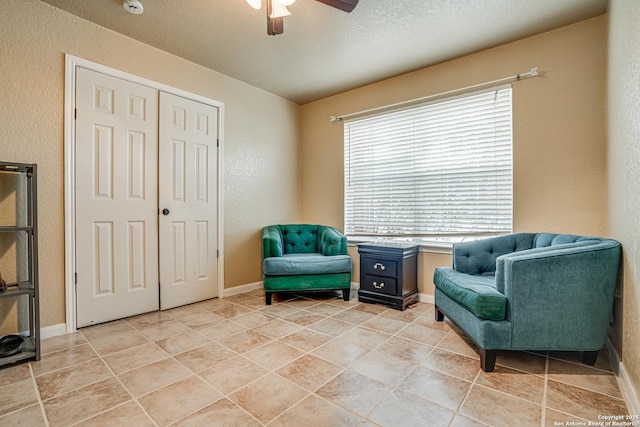 living area featuring ceiling fan and a textured ceiling