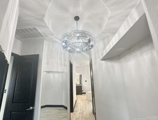 corridor featuring an inviting chandelier and light hardwood / wood-style floors