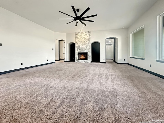 unfurnished living room with ceiling fan, a fireplace, and light carpet