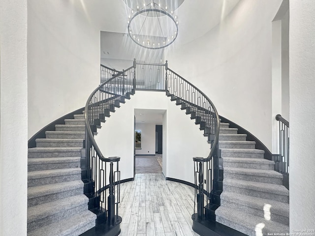 stairs featuring a high ceiling, hardwood / wood-style floors, and a notable chandelier