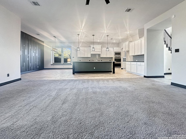 unfurnished living room featuring ceiling fan, sink, and light carpet