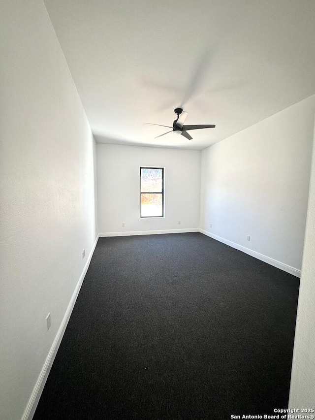 empty room with ceiling fan and dark colored carpet