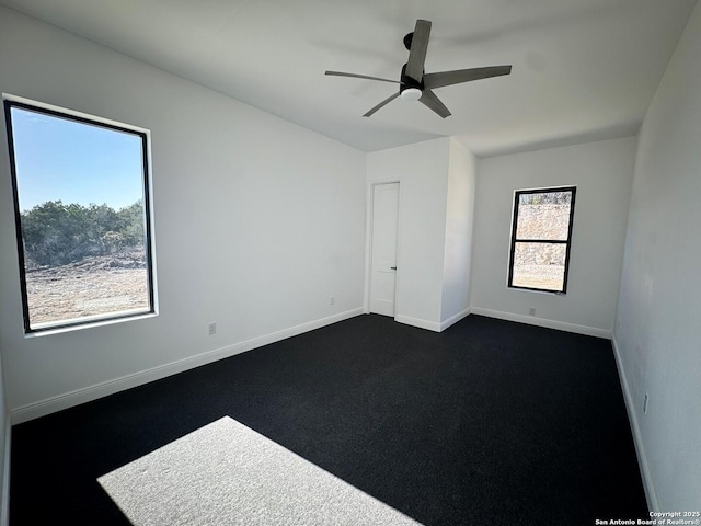 empty room featuring dark carpet and ceiling fan