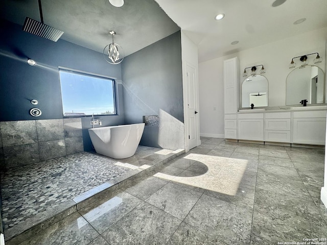 bathroom featuring vanity, a bathtub, and an inviting chandelier