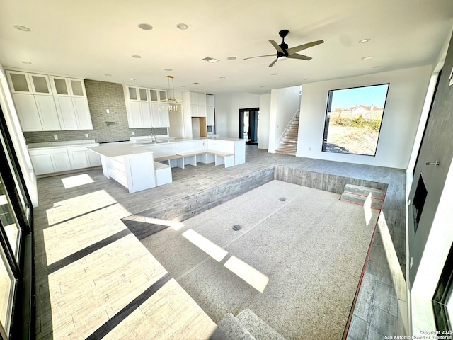 kitchen featuring a spacious island, white cabinetry, light hardwood / wood-style flooring, hanging light fixtures, and backsplash