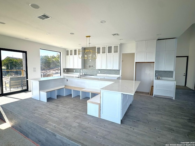 kitchen featuring white cabinetry, light hardwood / wood-style flooring, pendant lighting, and a spacious island