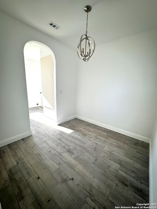 unfurnished room with a chandelier and dark hardwood / wood-style flooring