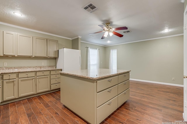 kitchen with a kitchen island, dark wood-type flooring, light stone counters, and cream cabinetry