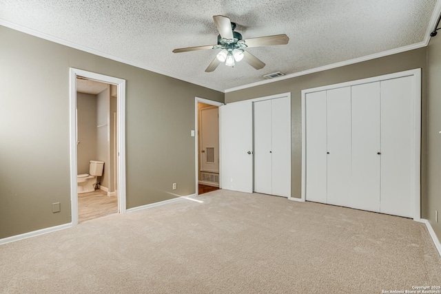 unfurnished bedroom with a textured ceiling, ornamental molding, and multiple closets