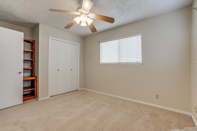 unfurnished bedroom with ceiling fan, light carpet, a textured ceiling, and a closet