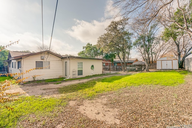 rear view of property with a lawn and a storage unit