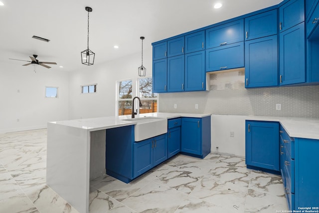 kitchen with pendant lighting, sink, ceiling fan, backsplash, and blue cabinets