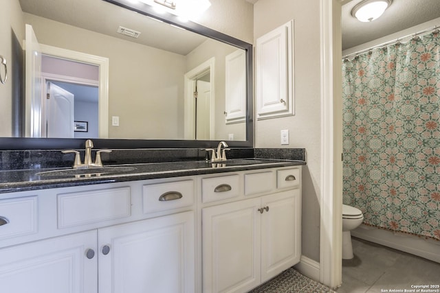 bathroom featuring walk in shower, vanity, toilet, and tile patterned flooring