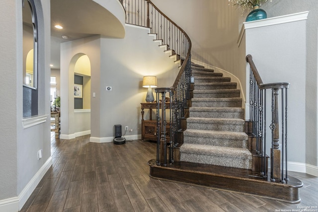 stairs with hardwood / wood-style floors and a high ceiling