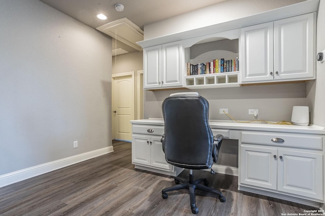 office with built in desk and dark wood-type flooring