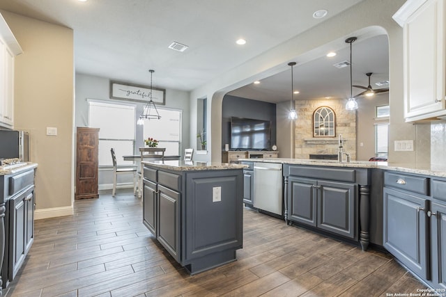 kitchen with gray cabinets, light stone countertops, a kitchen island, and hanging light fixtures