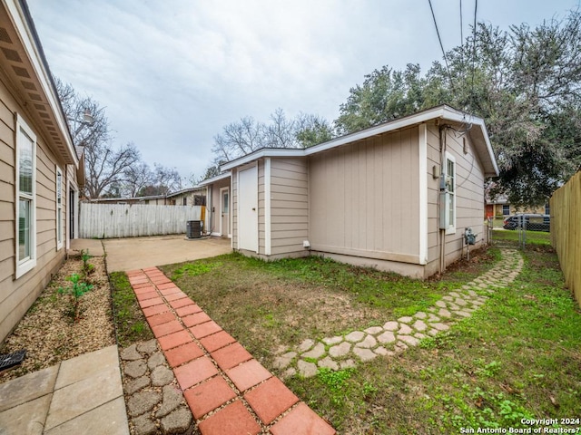 view of side of home featuring a lawn, a patio area, and central air condition unit