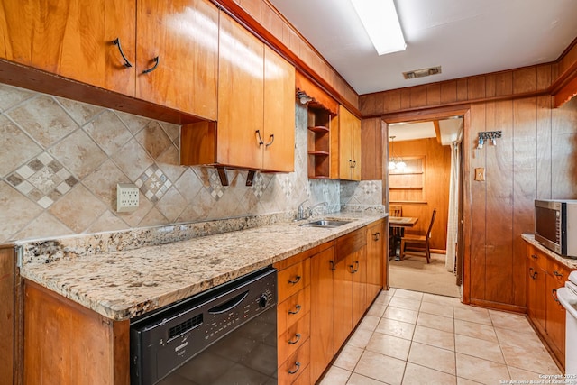 kitchen featuring wood walls, dishwasher, sink, decorative backsplash, and light stone countertops