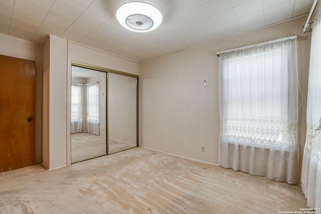 unfurnished bedroom featuring crown molding, light carpet, and a closet