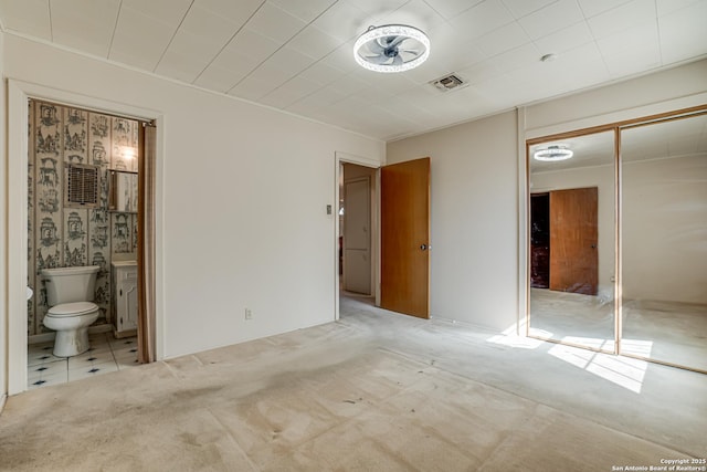 unfurnished bedroom with light colored carpet, ensuite bathroom, and a closet