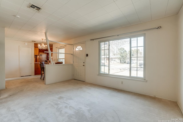 unfurnished living room with light carpet and an inviting chandelier