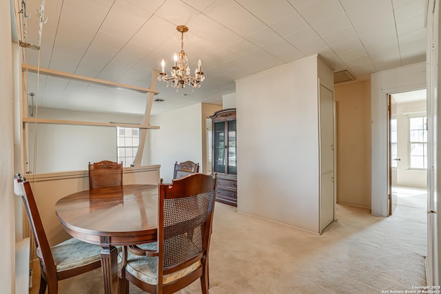 dining area with an inviting chandelier and light carpet