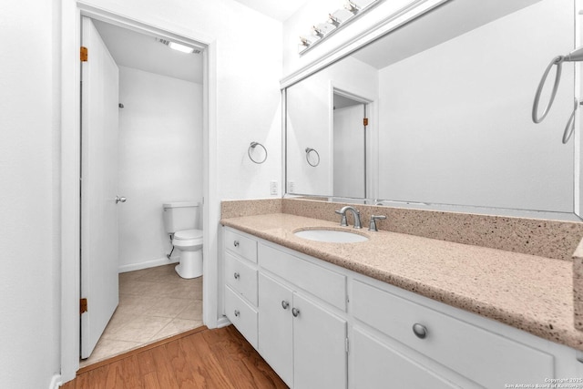 bathroom featuring wood-type flooring, toilet, and vanity