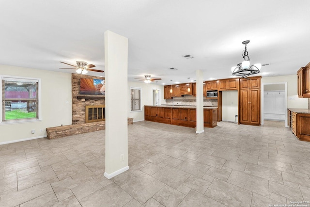 unfurnished living room featuring ceiling fan with notable chandelier and a fireplace