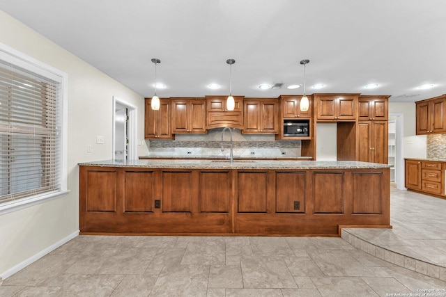 kitchen featuring black microwave, pendant lighting, kitchen peninsula, and decorative backsplash