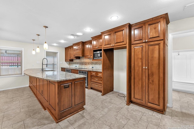 kitchen featuring sink, appliances with stainless steel finishes, backsplash, hanging light fixtures, and light stone counters