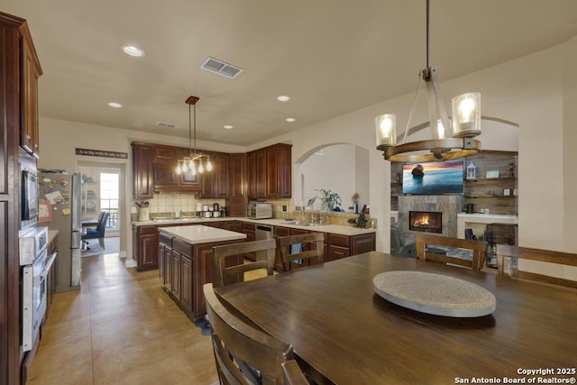 kitchen with decorative light fixtures, a chandelier, a kitchen island, a fireplace, and decorative backsplash