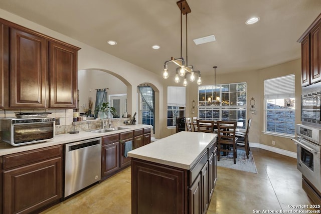 kitchen with tasteful backsplash, sink, hanging light fixtures, a center island, and stainless steel appliances