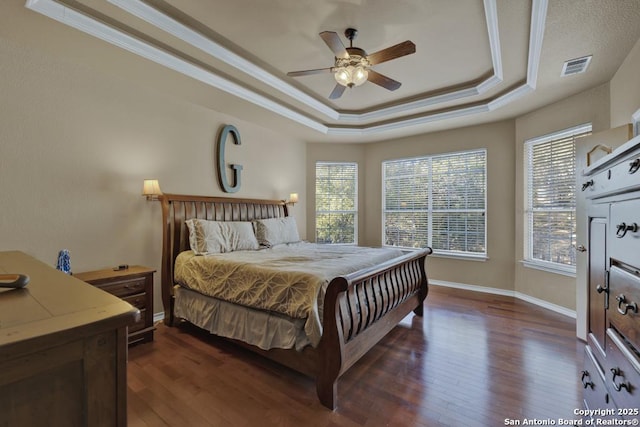 bedroom with dark hardwood / wood-style floors, ornamental molding, a raised ceiling, and ceiling fan