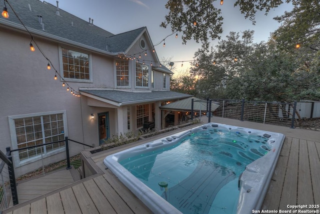 pool at dusk featuring a gazebo and a deck