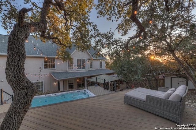 back house at dusk with a swimming pool side deck, outdoor lounge area, and a shed