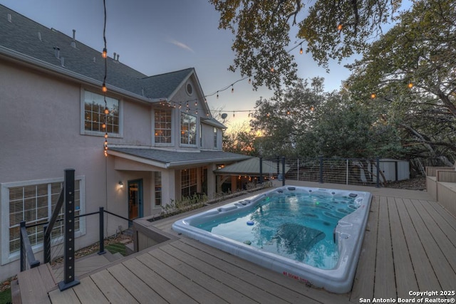 pool at dusk featuring a gazebo, a storage shed, and a wooden deck