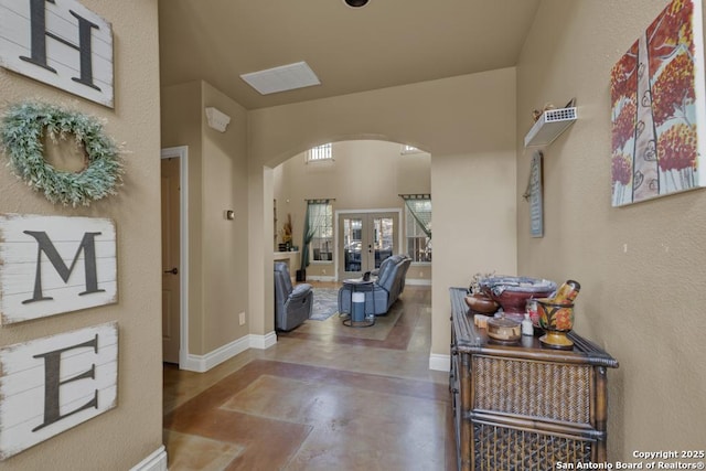 hallway with concrete floors, french doors, and a high ceiling