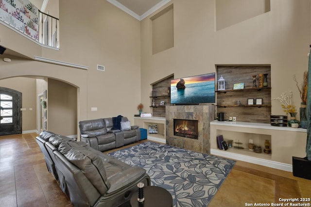 living room with ornamental molding, a towering ceiling, and a fireplace