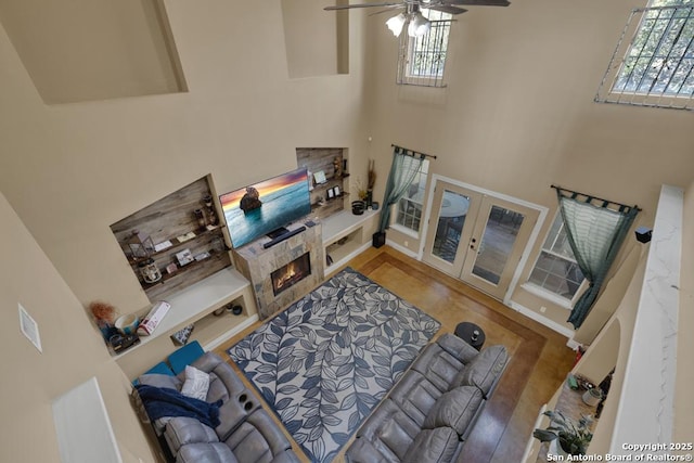 living room featuring french doors, ceiling fan, plenty of natural light, and a towering ceiling