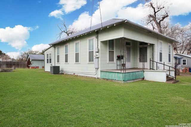 rear view of house featuring central AC and a lawn