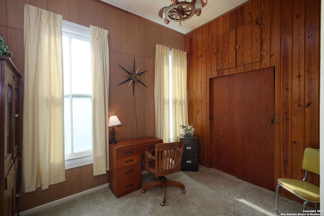 home office with plenty of natural light, a chandelier, light carpet, and wood walls