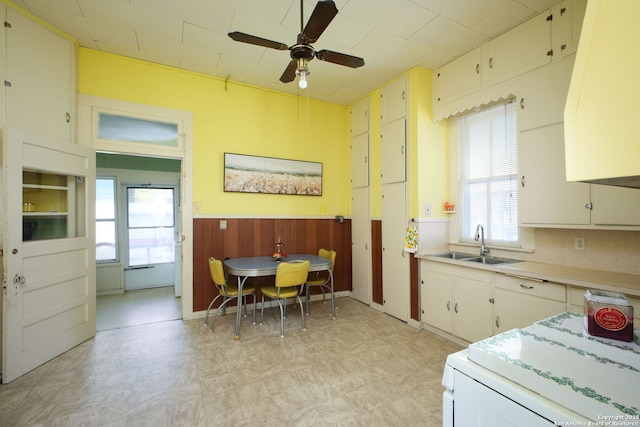 kitchen with white cabinetry, ceiling fan, sink, and stove