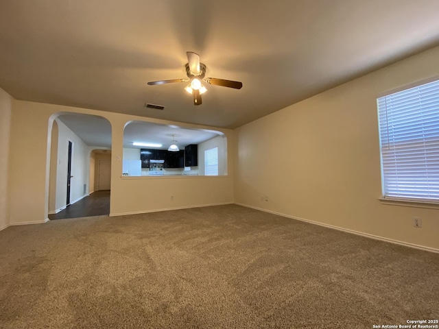 unfurnished living room with ceiling fan and dark colored carpet