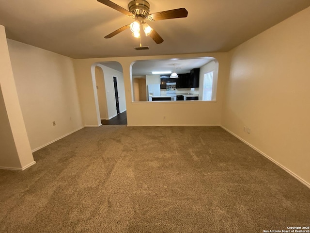 unfurnished living room featuring ceiling fan and dark colored carpet