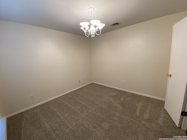 empty room with an inviting chandelier and dark carpet