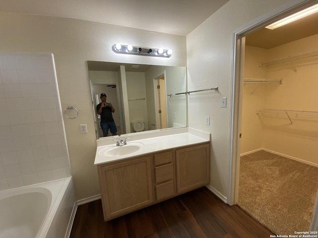 bathroom with wood-type flooring, a tub, vanity, and toilet