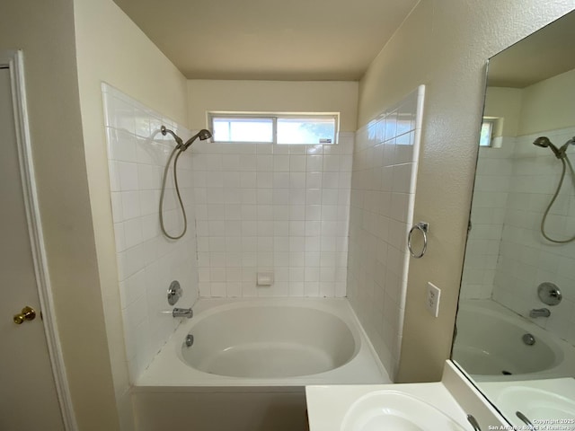 bathroom featuring tiled shower / bath combo and vanity