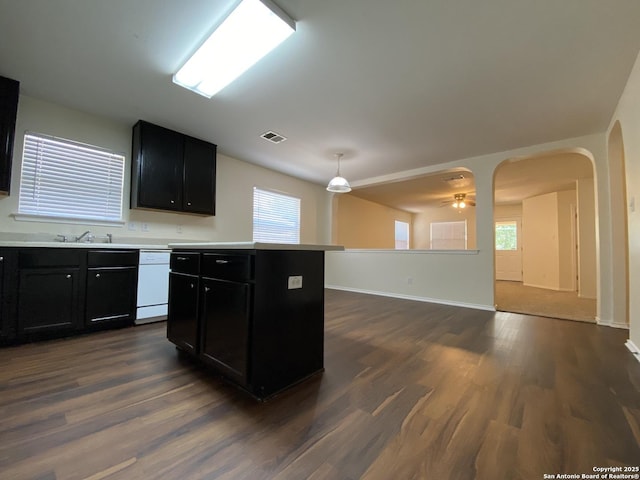 kitchen with ceiling fan, dishwasher, hanging light fixtures, a kitchen island, and dark hardwood / wood-style flooring