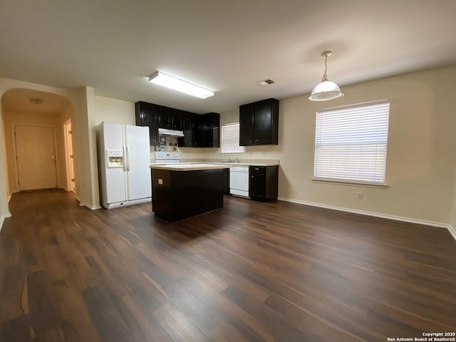 kitchen with dark wood-type flooring, white appliances, decorative light fixtures, and a kitchen island